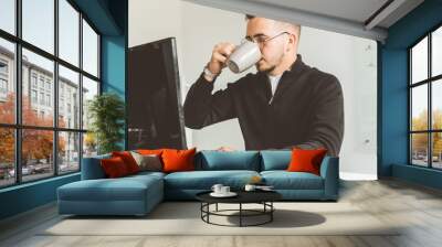 Young office worker sitting at desk, using computer. Two business man talking Wall mural