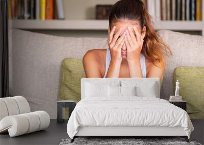 upset young girl sitting in a sofa at home Wall mural