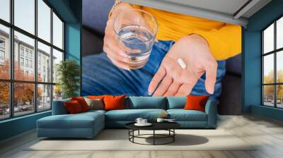 Close up young woman hands holding white pill and glass of water. Vitamins, pills and tablets. Health care and people concept. Wall mural