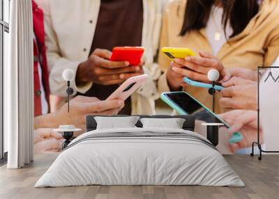 Closeup view of young group of people hands using mobile phone outdoors. Millennial people connected online browsing internet on smartphone device. Wall mural