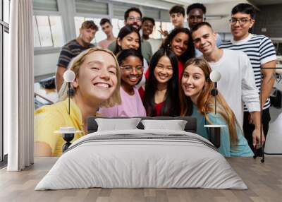 Diverse group of young student people taking selfie at university classroom. Millennial classmates posing with male teacher for self photo together. Education and community concept. Wall mural