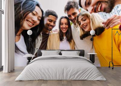 Group of young happy people using mobile phone at city street. Millennial diverse friends enjoying social media content on cellphone app. Technology lifestyle and youth community concept. Wall mural