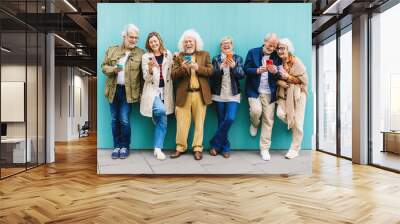 Happy senior adult people using mobile phones standing over isolated blue background. Communication and elderly lifestyle concept. Wall mural