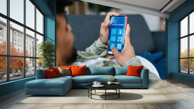 Internet of things. Young hispanic latin man using smart home app on mobile phone. IOT concept Wall mural