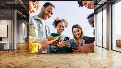 Young group of happy friends using smart mobile phone together outdoors. Multiracial teenage people having fun together sharing social media content on cellphone app. Technology lifestyle concept Wall mural