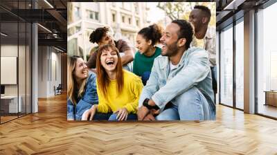 Young group of hispanic latin friends having fun together outdoors. Millennial multiracial people laughing while social gathering sitting on stairs at city street Wall mural