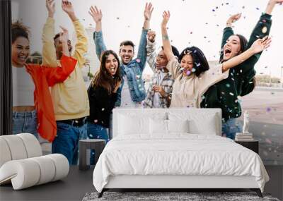 Young group of people having fun together enjoying outdoors party while throwing confetti. Millennial diverse friends celebrating at sunset Wall mural