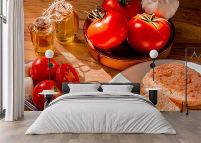 Receta típica Cataluña. Pan con tomate untado y aceite sobre encimera de madera y un bol con ajos.  Wall mural