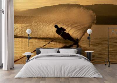 Silhouette of a Man practicing water ski slalom at a lake in the sunrise sunset making water spray in mexico Wall mural