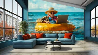 grandmother miss lady seniora in sunglasses and a panama hat with laptop swims on a ring in the sea Wall mural