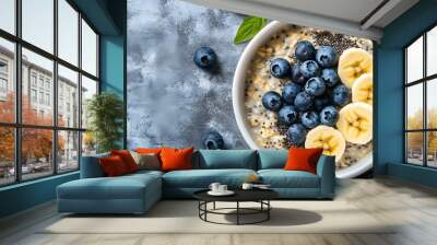 Bircher muesli or overnight oatmeal with apple, banana and blueberries in gray bowl, top view. Wall mural