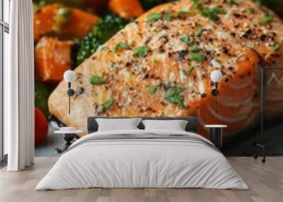 A close-up of a perfectly cooked salmon fillet with a sprinkle of black pepper and herbs on top, sitting on a plate with a side of roasted vegetables Wall mural