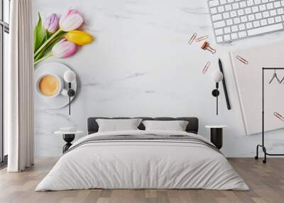 Office desk with computer, pink and yellow tulips, coffee cup and pink diary on white marble background. Flat lay. Copy space for text. Top view. Wall mural