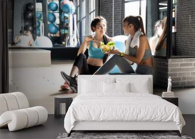 Healthy asian two people young woman eating vegetables green salad at gym In a room with a window with natural light. Fitness and healthy food concept Wall mural