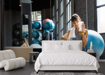 Young Asian Woman wiping sweat with towel in gym. Fitness and healthy lifestyle, Starting to exercise concept Wall mural