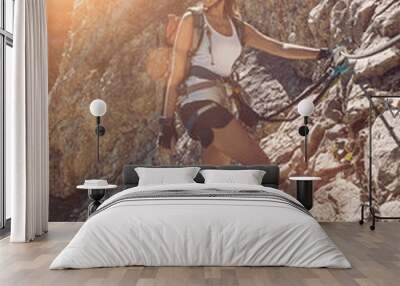 Young woman scaling a mountain in morning light Wall mural