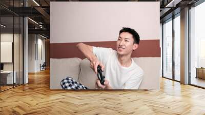 chinese young man sit on sofa play video game Wall mural