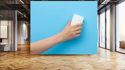 Hand holding sponge for cleaning on blue background Wall mural