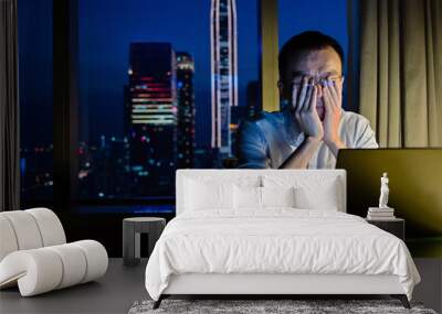 Tired man working with laptop at night Wall mural