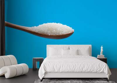 Wooden spoon with sugar crystals on blue background Wall mural