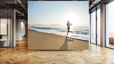 Young man running along beach  in the morning Wall mural