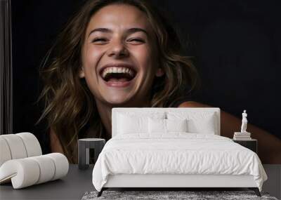 Portrait of a young woman laughing, black background with copy space Wall mural