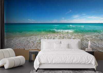 Turquoise waves gently crashing on a sandy beach under a clear blue sky, creating a serene and beautiful scene. Wall mural