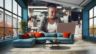 Beautiful afro american lady working on laptop in modern office Wall mural