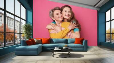 Beautiful woman and her charming daughter looking away in studio Wall mural