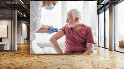 Best treatment for you. Portrait of bearded old man receiving vaccine shot in hand while sitting on hospital bed Wall mural