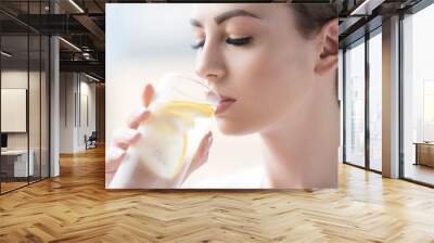 Calm youthful lady refreshing herself with lemon water Wall mural