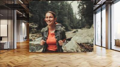 Cheerful attractive woman traveling near mountain river while spending weekend with pleasure Wall mural