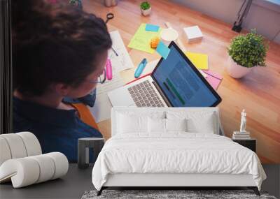 Cheerful female worker is typing on notebook Wall mural