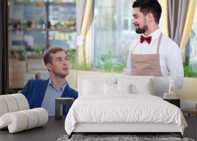 cheerful male cafe worker is serving a customer Wall mural