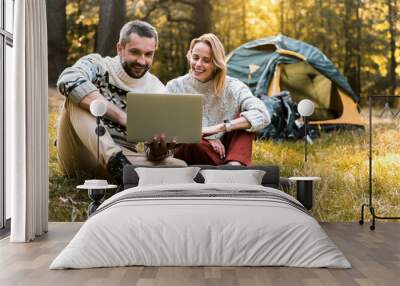 Cheerful man and woman using portable computer in the nature Wall mural