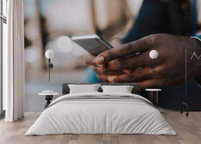 Close up of a modern mobile phone used by an afro american young man Wall mural