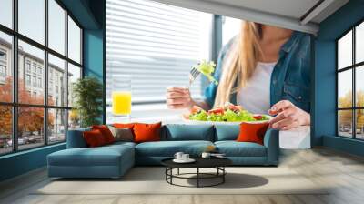 close up of cheerful young woman eating fresh salad and smiling. focus on plate on the table. copy s Wall mural