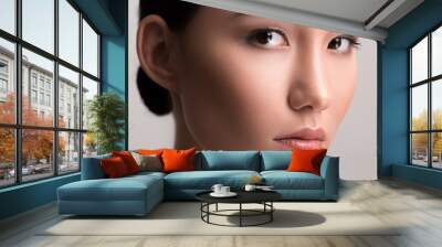 Close-up of face of young asian woman with perfect and soft skin. She is looking at camera dreamily. Isolated background Wall mural