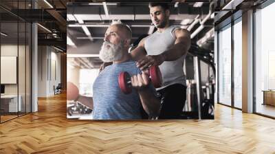 Concentrated senior male is training his biceps in gym Wall mural