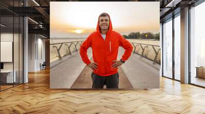 Cute athletic man standing on a bridge Wall mural