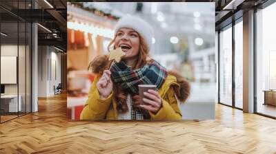 Delighted young woman biting tasty Christmas biscuit Wall mural