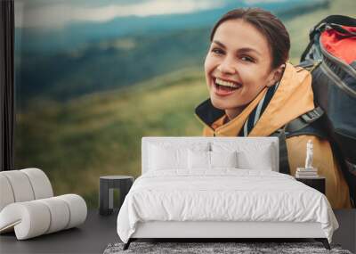 Delighted young woman resting on the slopes of the mountain while feeling happy Wall mural