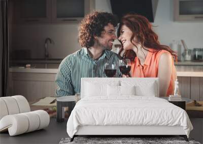 Excited loving couple is celebrating special event with wine. They are looking into each other eyes with affection and laughing. Romance concept  Wall mural