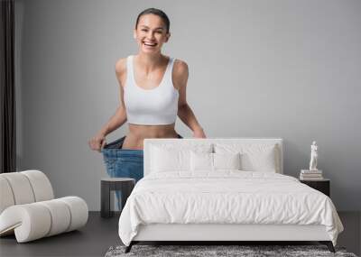 Excited young woman wearing oversized jeans after fitness Wall mural