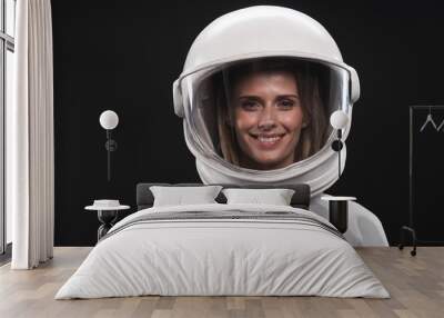 Feeling happiness. Portrait of charming delighted female astronaut wearing helmet and protective suit is standing and looking at camera with wide smile. Isolated background Wall mural