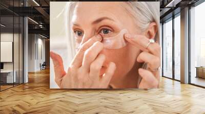 Female is looking into the mirror while wearing eye patches against wrinkles Wall mural