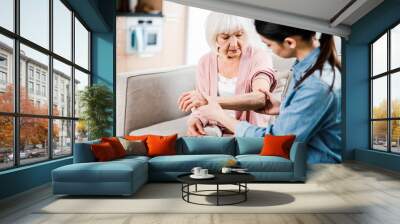 Female physician checking arm of elderly woman Wall mural