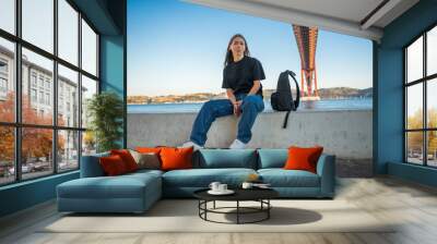 Female teenager looking at the camera and sitting with her skateboard Wall mural