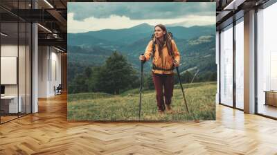 Full length of a nice sporty female traveler using Nordic walking sticks while having an active weekend in the mountains Wall mural