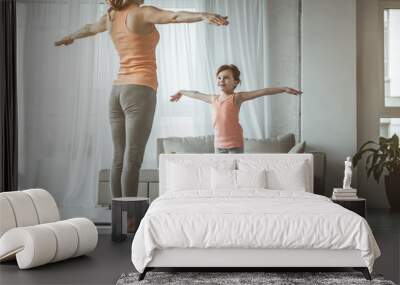 Full length portrait of woman and child standing in hands to the sides position. Home fitness is fun and joyful for girl. She is encouraged and pleased Wall mural